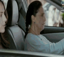 a woman is driving a car with another woman sitting in the back seat behind her