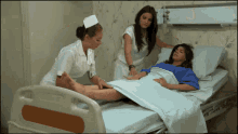 a woman in a hospital bed with two nurses standing around her