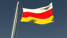 a red white and yellow flag flies in the wind