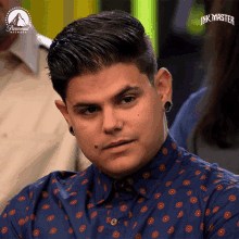 a man wearing a blue shirt that says ' inkmaster ' on it