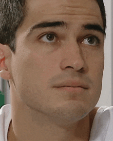 a close up of a man 's face with a white shirt on .