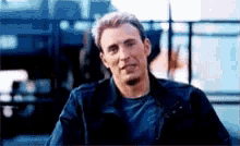 a close up of a man wearing a blue shirt and a leather jacket .