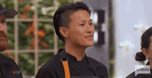 a woman in a chef 's uniform is smiling while standing in a kitchen .