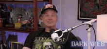 a man is sitting in front of a microphone wearing a t-shirt that says ' dark web ' on it