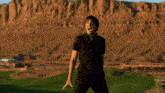 a man in a black shirt stands on a golf course