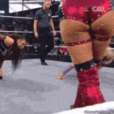 a woman is kneeling down in a wrestling ring while a referee watches .