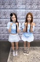 two girls standing next to each other in front of a wall that has a prada logo on it