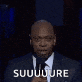 a man in a suit and tie is making a funny face and saying suuuure .