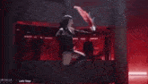 a woman is dancing on a stage while holding a red fan in her hand .