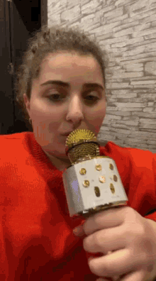 a woman is holding a microphone in her mouth and singing into it .