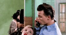 a man is kissing a woman on the cheek while talking on a payphone .