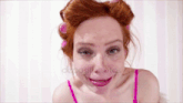 a woman with red hair and curlers in her hair is making a funny face .