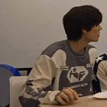a man wearing a performance ultra sweatshirt sits at a desk