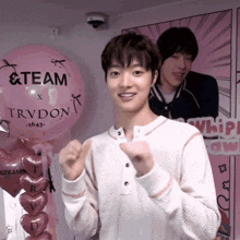 a man stands in front of a pink balloon that says team on it