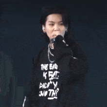 a man is singing into a microphone while wearing a black shirt .