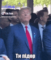 a man in a suit and tie is standing in a crowd of people and making a funny face .