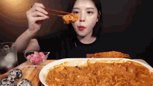 a woman is eating a plate of food with chopsticks and a bowl of pickles
