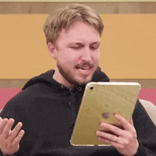 a man with a beard is holding an apple ipad