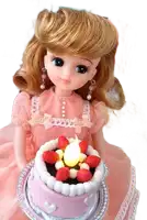 a doll in a pink dress is holding a small cake