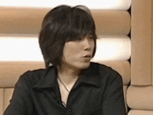 a man in a black shirt is sitting in front of a wall