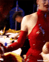 a woman in a red dress and gloves is standing in front of a table ..