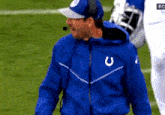 a man wearing a blue jacket with a horseshoe logo on it