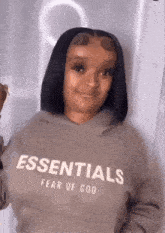 a woman wearing a essentials fear of god sweatshirt