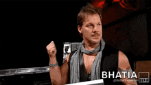 a man with a scarf around his neck is standing in front of a sign that says you just made .