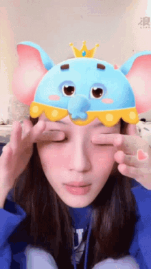 a woman wearing a blue elephant mask with a crown on top