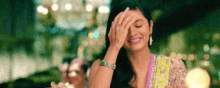 a woman is laughing and covering her face with her hand .