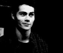 a black and white photo of a young man in a plaid shirt .