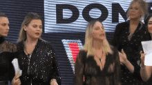 a group of women are standing in front of a sign that says dom .