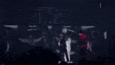 a man in a white suit is dancing on a stage in the dark .