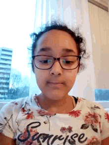 a girl wearing glasses and a floral shirt that says surprise