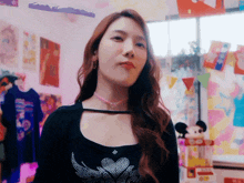 a woman wearing a choker and a black top is standing in front of a window