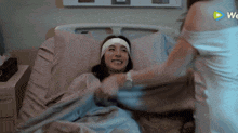 a woman is laying in a hospital bed with a headband on her head