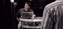 a man is sitting at a table with a laptop on it .