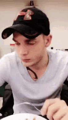 a man wearing a baseball cap and a white shirt is eating