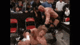 two wrestlers are wrestling in a ring in front of a crowd .