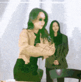 a woman with green hair is wearing sunglasses and a jacket that says jesus on it