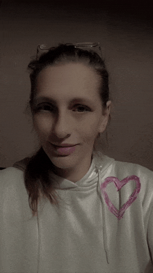 a woman wearing a white sweatshirt with a pink heart on the front