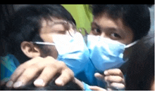 two men wearing face masks are kissing each other on the cheek .