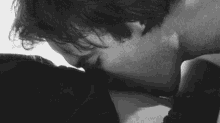 a black and white photo of a man kissing a woman on the neck .
