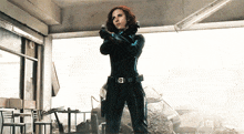 a woman in a black suit is holding a gun with a belt that says ' avengers '