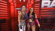 two female wrestlers are standing next to each other in front of a wall that says r on it