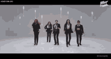 a group of women in tuxedos are dancing in front of a white background .