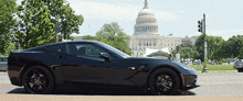 a black sports car is parked on the side of the road in front of the capitol building