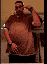a man wearing glasses and a watch is standing in front of a mirror with tiktok written on the bottom