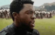 a man with a beard is standing in a field with a crowd of people behind him .