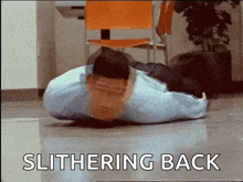 a man is laying on his back on the floor with the words slithering back written on the bottom .
